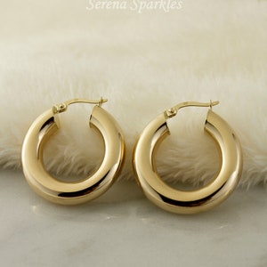 May include: A pair of gold hoop earrings. The hoops are thick and have a smooth, polished finish.