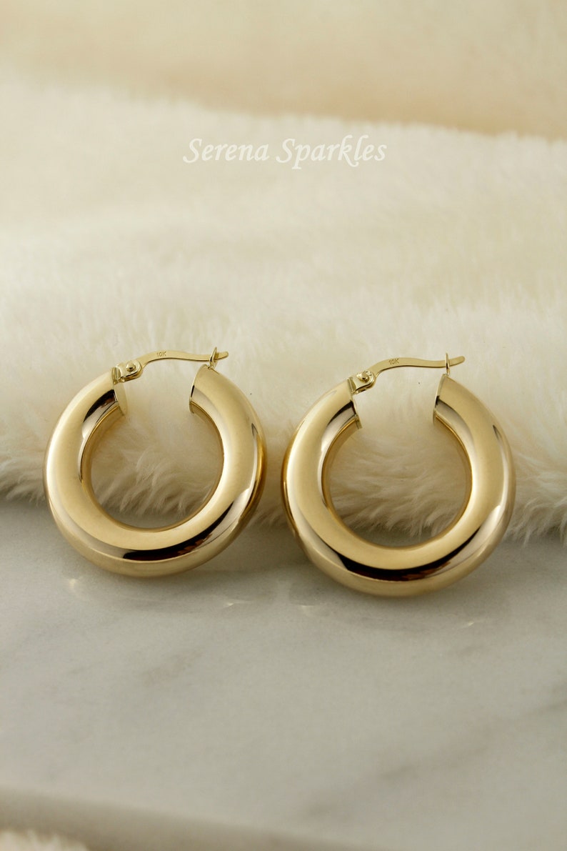 May include: A pair of gold hoop earrings. The hoops are thick and have a smooth, polished finish.