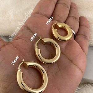 May include: Three gold hoop earrings of different sizes, 10mm, 15mm, and 20mm, shown on a hand.