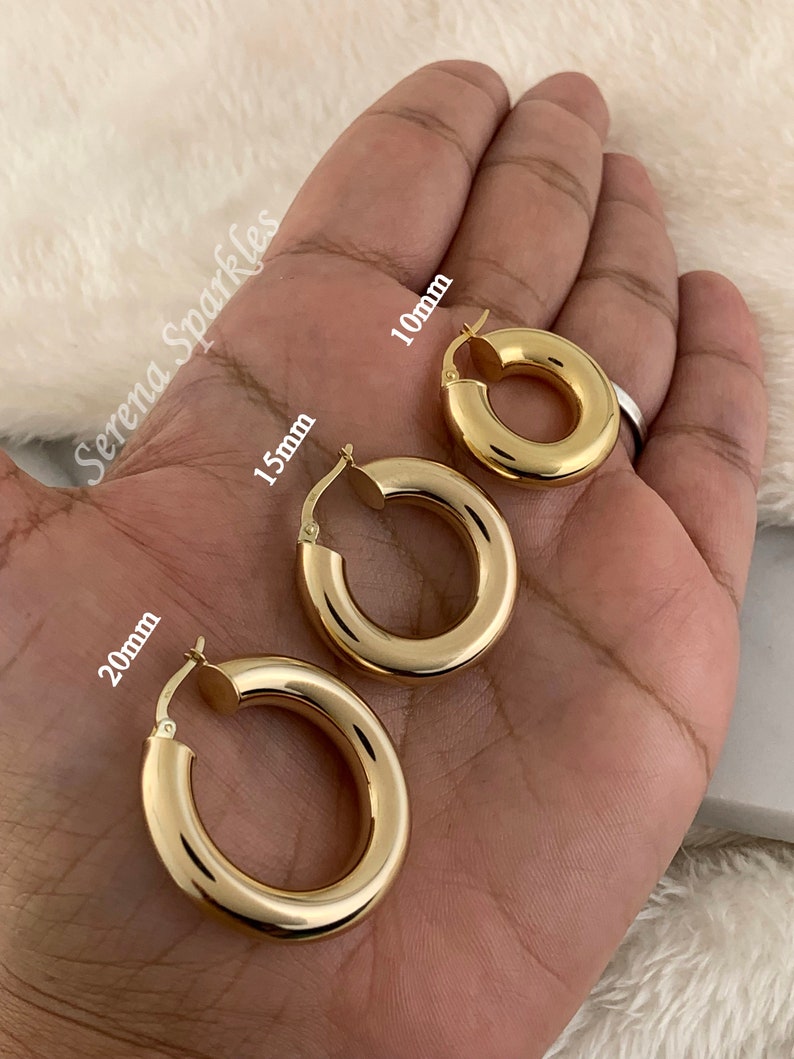 May include: Three gold hoop earrings of different sizes, 10mm, 15mm, and 20mm, shown on a hand.