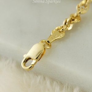 May include: Close-up of a gold chain necklace with a lobster clasp. The chain is made of small, round links.