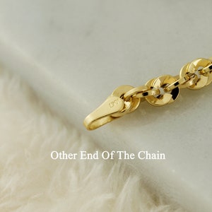May include: Close-up of a gold chain with a clasp that reads "10K". The chain is on a white fuzzy surface.