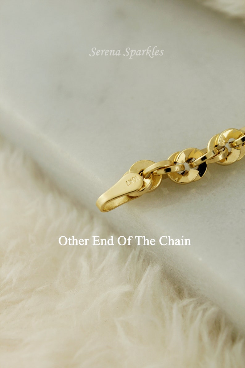 May include: Close-up of a gold chain with a clasp that reads "10K". The chain is on a white fuzzy surface.