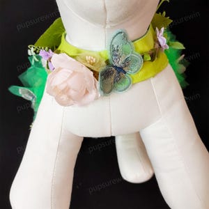 May include: A green and white dog collar with a pink flower, green leaves, and a blue butterfly applique.