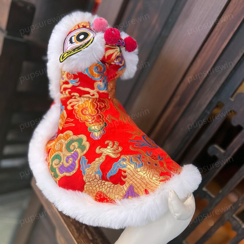 May include: Red and gold Chinese dragon costume for a pet. The costume has a white fur trim and a lion head with a white fur mane.