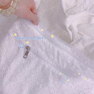 May include: White lace fabric with a zipper and the text "pocket on the back".