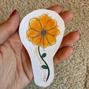 May include: A die-cut sticker featuring a watercolor-style sunflower with orange petals and a dark brown center. The stem is green with leaves, and the text "grow your repertoire" is written in cursive.