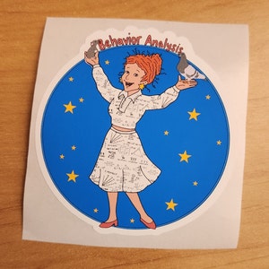 Pu&ograve; includere: Un adesivo blu e bianco con una donna dei cartoni animati che tiene un uccello e un topo. La donna indossa un vestito bianco con un motivo di equazioni matematiche. L'adesivo dice "Behavior Analysis" su uno striscione bianco.