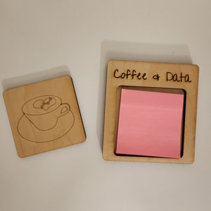 May include: Wooden desk organizer with a square frame holding a stack of pink sticky notes. The text "Coffee & Data" is etched on the frame. A separate wooden coaster with a coffee cup design is also present.