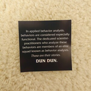 May include: A black and white sticker with the text "In applied behavior analysis, behaviors are considered especially functional. The dedicated scientist-practitioners who analyze these behaviors are members of an elite squad known as behavior analysts. These are their stories. DUN DUN."