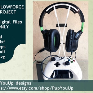 Könnte beinhalten: Ein weißer Gaming-Controller mit einem schwarzen Headset-Ständer. Der Ständer ist aus weißem Kunststoff und hat einen grünen Akzent. Das Headset ist schwarz mit grünen Akzenten. Der Controller und der Ständer befinden sich auf einer Glasoberfläche. Das Bild enthält den Text "GLOWFORGE PROJECT" und "Digital Files ONLY" in einem dunkelblauen Kasten. Der Text unter dem Bild lautet "PupYouUp designs" und "https://www.etsy.com/shop/PupYouUp".