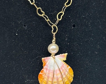 May include: A seashell pendant necklace with a gold-colored chain. The pendant features a natural seashell in shades of orange, yellow, and pink, with gold wire detailing and a pearl bead. The chain has a heart-shaped link design.