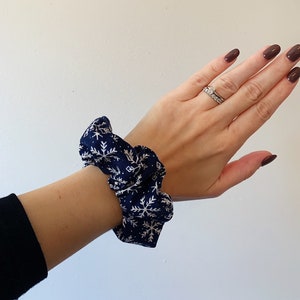 May include: A navy blue scrunchie with a white snowflake pattern.