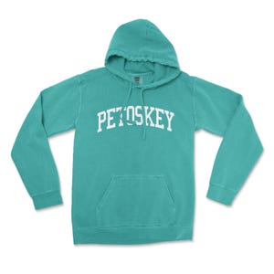 May include: A turquoise blue hooded sweatshirt with a white embroidered arch that reads "Petoskey".