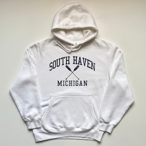 May include: White hooded sweatshirt with a navy blue print that says "South Haven Michigan" with two crossed oars.