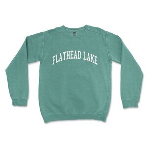 May include: A teal blue sweatshirt with the text "FLATHEAD LAKE" in white.