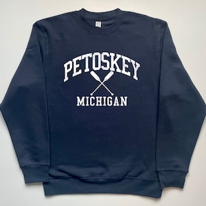 May include: A navy blue sweatshirt with a white graphic print that says "Petoskey Michigan" with two crossed paddles.