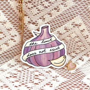 May include: A sticker with a purple fig illustration and the text "the limit does not exist". The sticker is on a white lace background. There is a small pink heart sticker next to the fig sticker.