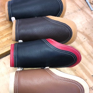 Pu&ograve; includere: Quattro braccialetti in pelle con cuciture a contrasto. I braccialetti sono in nero, marrone, nero con cuciture rosse e marrone con cuciture bianche.