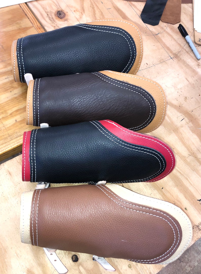 Pu&ograve; includere: Quattro braccialetti in pelle con cuciture a contrasto. I braccialetti sono in nero, marrone, nero con cuciture rosse e marrone con cuciture bianche.