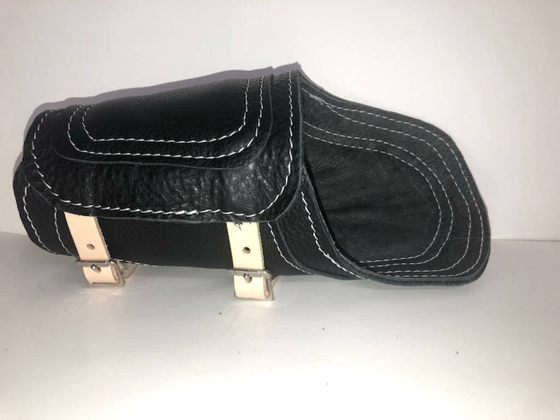 Pu&ograve; includere: Sella da moto in pelle nera con cuciture bianche e fibbie color crema.