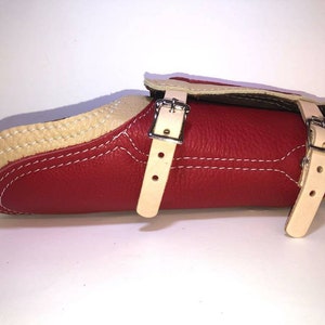 Pu&ograve; includere: Parabraccio in pelle rossa con due cinturini regolabili e fibbie. Il parabraccio &egrave; foderato in pelle color crema.
