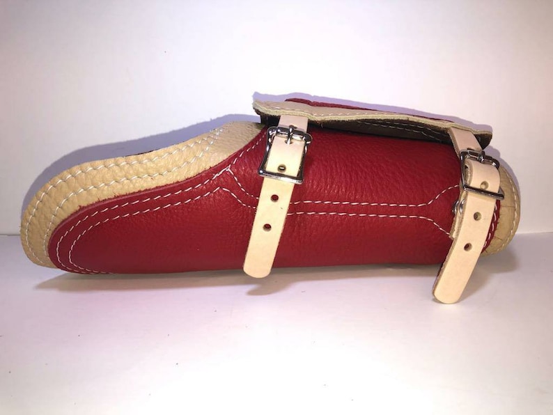 Pu&ograve; includere: Parabraccio in pelle rossa con due cinturini regolabili e fibbie. Il parabraccio &egrave; foderato in pelle color crema.
