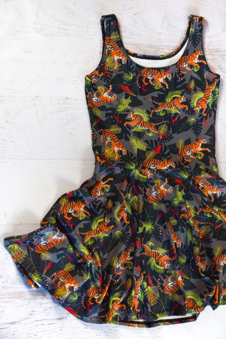 May include: A sleeveless dress with a black background and a pattern of orange tigers and green leaves.