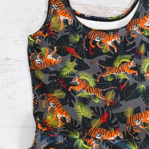 May include: A sleeveless dress with a gray background and a pattern of orange and black tigers in a jungle setting.
