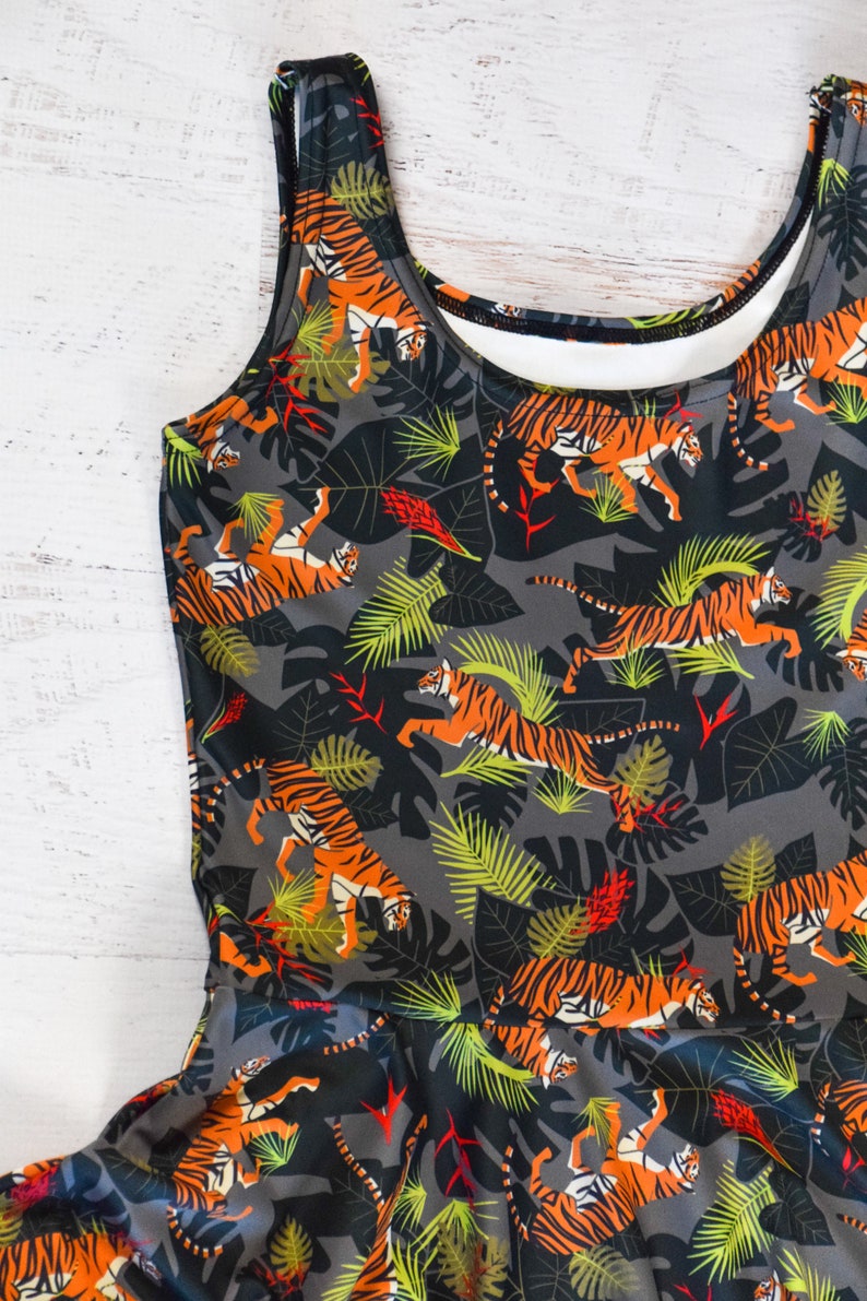 May include: A sleeveless dress with a gray background and a pattern of orange and black tigers in a jungle setting.