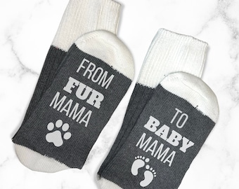 May include: A pair of gray and white socks with the text "From Fur Mama to Baby Mama" on them. One sock has a paw print and the other has a footprint.