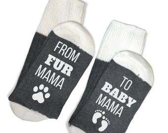 May include: Pair of grey and white socks with the text "From Fur Mama to Baby Mama" on them. One sock has a paw print and the other has a footprint.