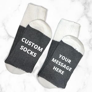 May include: A pair of gray and white socks with the text "CUSTOM SOCKS" on one sock and "YOUR MESSAGE HERE" on the other sock.
