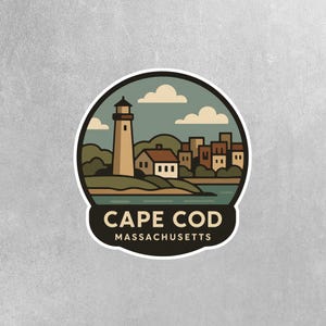 May include: A round sticker featuring a lighthouse, houses, and a body of water. The sticker has a black border and the words "CAPE COD MASSACHUSETTS" in white text at the bottom. The background is a light gray.