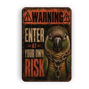 May include: A rectangular metal sign with a distressed finish featuring a green parrot wearing a metal chain around its neck. The text reads WARNING ENTER AT YOUR OWN RISK in bold, weathered orange and white lettering against a dark background.
