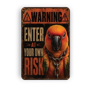 May include: A rectangular metal sign with a distressed orange and black finish. The text reads WARNING ENTER AT YOUR OWN RISK. A vibrant orange and yellow parrot with a dark beak is depicted wearing a metallic chain around its neck.