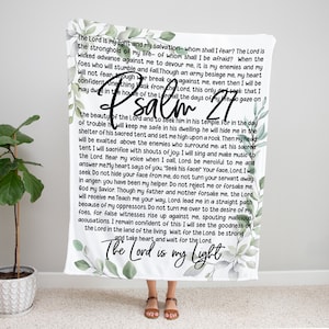 May include: White throw blanket with a watercolor floral design and the text "The Lord is my light" and "Psalm 27" in black lettering. The text includes a passage from the Bible.