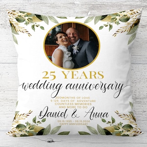Op de afbeelding: Een wit kussen met een gouden en groen bloemenontwerp. Het kussen heeft een foto van een stel in het midden, met de tekst "25 YEARS wedding anniversary" en "300MONTHS OF LOVE 9 125 DAYS OF ADVENTURE COUNTLESS MEMORIES AND MORE TO GO Daniel & Anna 08.16.1999-08.16.2024 HAPPY ANNIVERSARY".