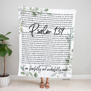 Puede incluir: Una manta blanca con un diseño floral verde y el texto "Salmo 139" y "Soy hecho de manera asombrosa y maravillosa" en letras negras. El texto es una cita de la Biblia.