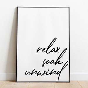 May include: Black and white framed print with the text "relax soak unwind" in a handwritten font.