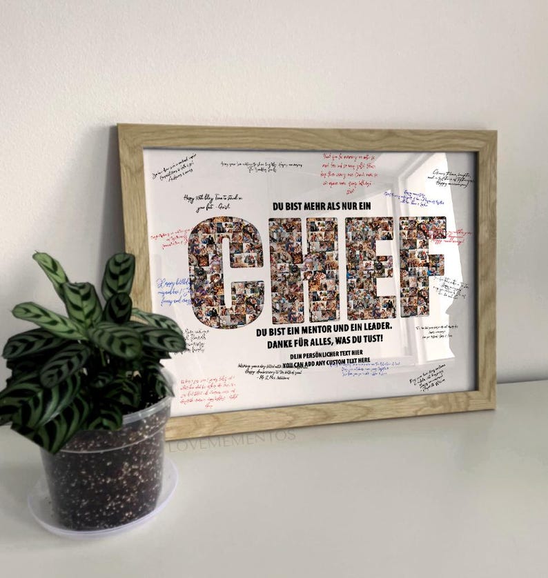 May include: Framed print with the word "CHEF" in large letters, composed of smaller images. The print includes text in German, signatures, and is in a light wood frame. A potted plant is in the foreground.