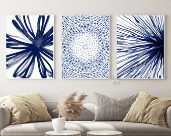 May include: A set of three rectangular wall art prints featuring abstract navy blue ink designs on white backgrounds. The left print shows bold radiating strokes, the centre displays a circular dotted pattern, and the right features fine lines.