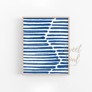 May include: Abstract art print featuring a blue and white striped pattern. The stripes are painted in a brushstroke style, creating a textured look. The print is framed in a light wood frame.