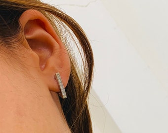 May include: A pair of silver bar earrings with small clear cubic zirconia stones set into the metal.