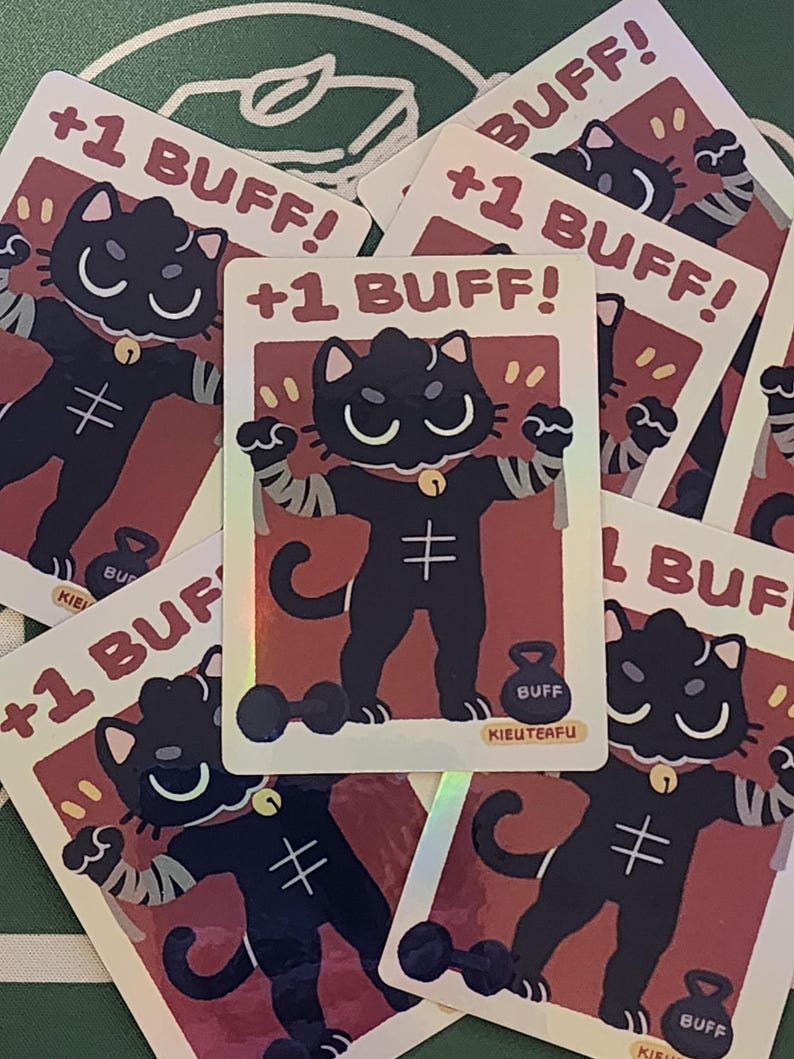 May include: A collection of trading cards featuring a black cat character with a gold bell collar and a weightlifting theme. Each card has the text "+1 BUFF!" and the word "BUFF" on a weight. The cards have a red background.