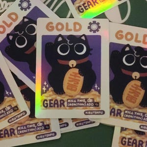 May include: A collection of trading cards featuring a black cat illustration. The cards have a gold and purple color scheme with the word "GOLD" at the top. The cat is holding a gold coin. The word "GEAR" is also visible.