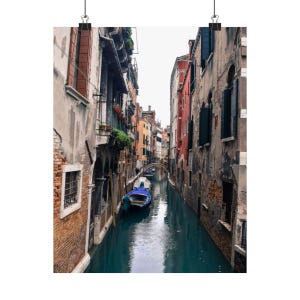 May include: A narrow canal in Venice, Italy, with colorful buildings lining the sides. A blue gondola is docked in the water.