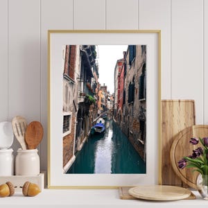 May include: A photograph of a narrow canal in Venice, Italy. The canal is lined with colorful buildings and a gondola is floating in the water.