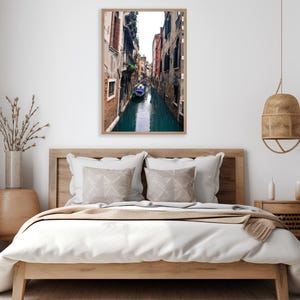 May include: A photograph of a narrow canal in Venice, Italy. The canal is lined with colorful buildings and a small boat is floating in the water.