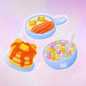 Puede incluir: Tres pegatinas azules y blancas con ilustraciones de alimentos para el desayuno. La primera pegatina muestra una sart&eacute;n azul con un huevo frito, tocino y una ramita de perejil. La segunda pegatina muestra una pila de panqueques con jarabe y una porci&oacute;n de mantequilla. La tercera pegatina muestra un taz&oacute;n azul lleno de cereal colorido y una cuchara.